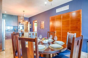A dining area with a round table set for four, surrounded by wooden chairs.
