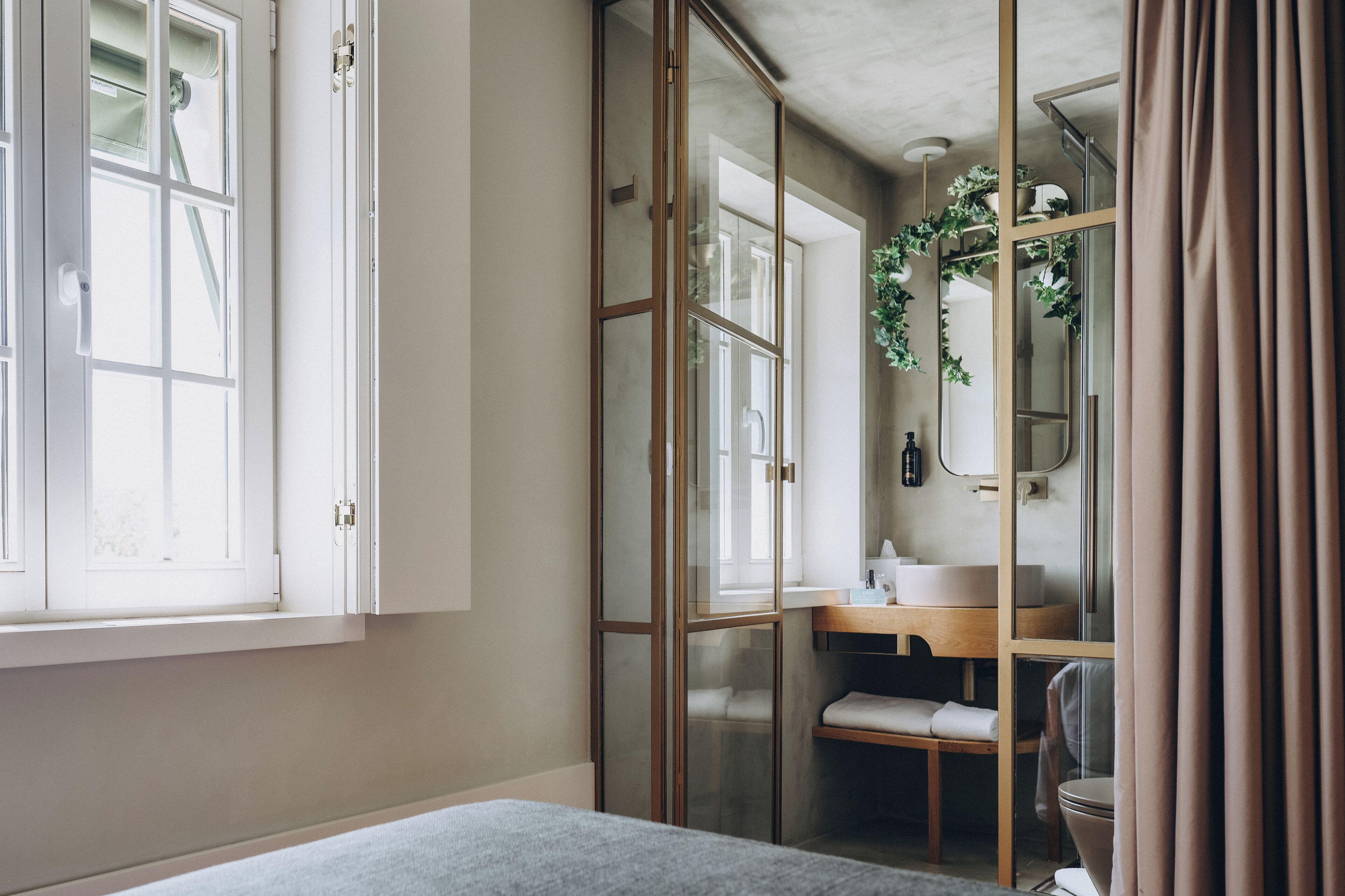 A bedroom with a bed, a window, a bathroom with a sink, and a shower.