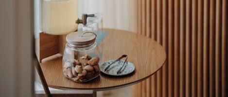 A wooden reception desk with a sign, a round table with a jar of cookies, a lamp, and a plate with a spoon.
