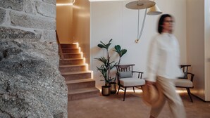 Un interior moderno con pared de piedra, una escalera y una zona de estar con plantas.