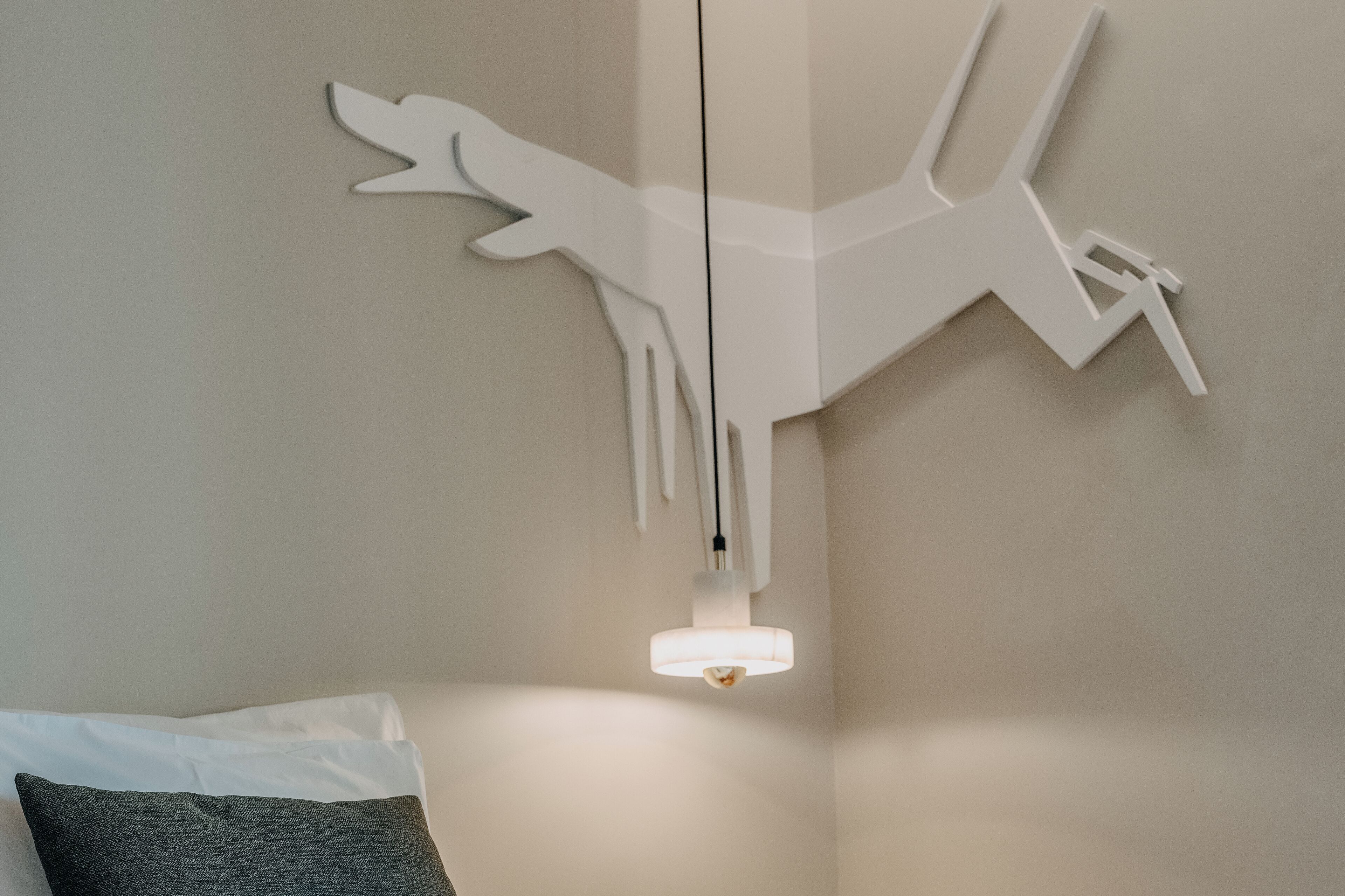 A modern room with a unique wall art piece and a hanging light fixture.