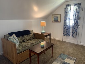 Uma sala de estar acolhedora com um sofá de madeira, uma mesinha com uma vela e um tapete estampado.