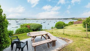 A picnic table with benches and chairs, overlooking a body of water with boats. - The Terrace 2 (Wadebridge)