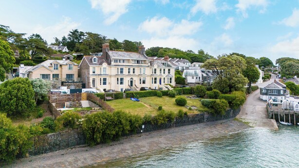 A large, multi-story house with a well-maintained lawn and a dock by the water. - The Terrace 2 (Wadebridge)