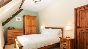 A bedroom with a wooden bed, a nightstand, a dresser, a wardrobe, and a chandelier. - 1 Old Thatch (Bridgwater)