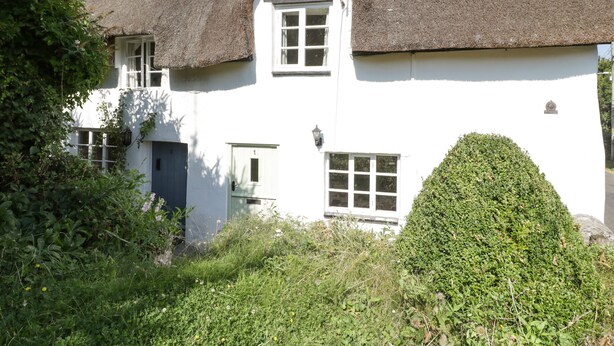 A white building with a thatched roof, a small door, and a window. - 1 Old Thatch (Bridgwater)