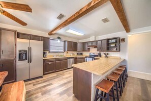 A modern kitchen with stainless steel appliances, wooden beams, and a central island with bar stools.