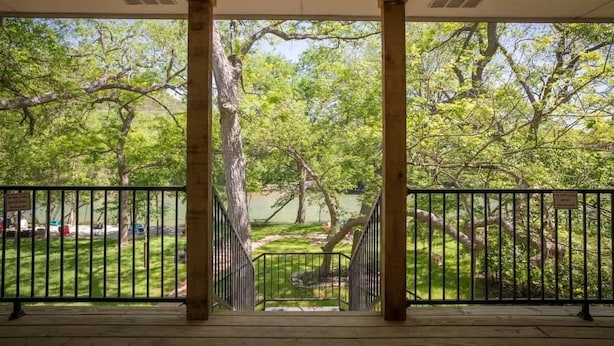 A covered outdoor area with a view of a park and a lake.