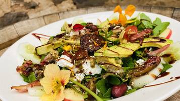 A white plate with a salad on a wooden table.