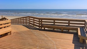 A wooden boardwalk leading to a beach with a wooden railing and benches. - This spacious home has sophisticated beach decor, adding to the welcoming feel t (Port Aransas)