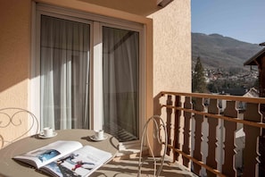 A balcony with a table, chairs, and a magazine.