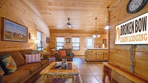 A cabin with a wooden interior, a couch, a coffee table, and a sign reading "Broken Bow Cabin Lodging".