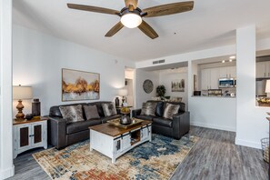 A modern living room with a dark leather sofa, a wooden coffee table, and a patterned rug.