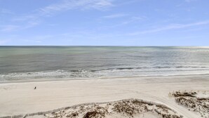 A beach with a sandy shore, a fence, and a person walking. - Great Rates*Beach Front Lazy River*Sleeps10*Oasis(formerly PW2) 802*8th floor (Orange Beach)