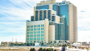 A multi-story hotel with a modern architectural design, featuring a prominent central tower and a symmetrical facade. - Great Rates*Beach Front Lazy River*Sleeps10*Oasis(formerly PW2) 802*8th floor (Orange Beach)