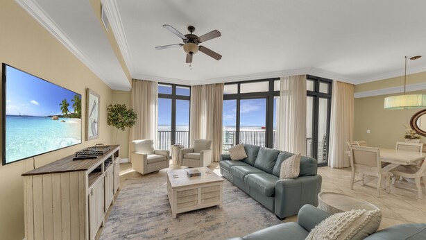 A spacious living room with a large TV, comfortable seating, a ceiling fan, and a view of the ocean. - Great Rates*Beach Front Lazy River*Sleeps10*Oasis(formerly PW2) 802*8th floor (Orange Beach)