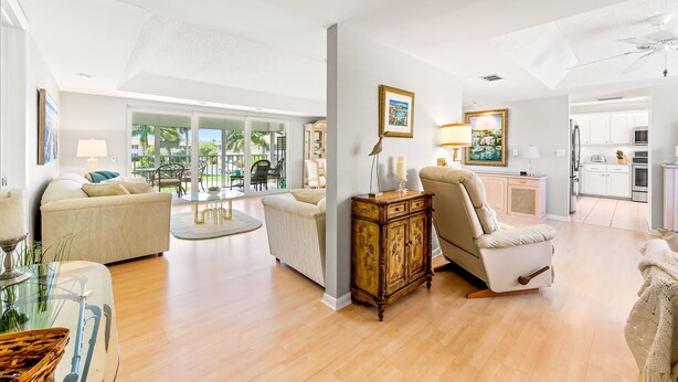 A spacious living room with a large window, a dining area, and a kitchen in the background. - Glades Golf & Country Club-Large, Updated 2/2 Condo near  Shopping, Beach & Pier (Naples)