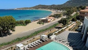 Una piscina con sillones de descanso y vistas al mar y a las montañas.