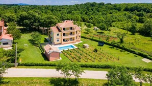 Ein mehrstöckiges Gebäude mit Swimmingpool, umgeben von üppiger Vegetation und Weinbergen.