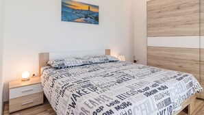 Ein Schlafzimmer mit einem Bett, einem Nachttisch, einer Lampe und einem Gemälde an der Wand.