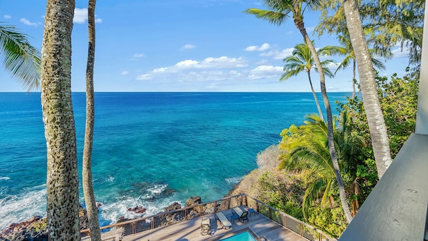 A wooden deck with lounge chairs and a pool overlooking the ocean. - Poipu Palms 303 By Parrish Kauai - oceanfront views & walk to beach (Koloa)