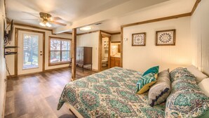 A spacious bedroom with a large bed, a ceiling fan, and a view of the backyard through a sliding door. - Hondo's River Haus Rr 1300 4 Bedroom Home by RedAwning (New Braunfels)