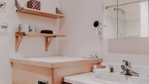 A modern bathroom with a wooden vanity, a white sink, and a mirror. There are two wooden shelves above the vanity, and a towel rack is mounted on the wall. - 18sll - Newly Remodeled - Sleeps 4 - Fireplace - W/d 1 Bedroom Condo by RedAwning (Deming)