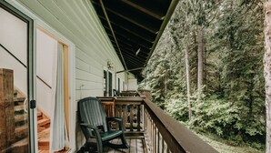 A wooden deck with a chair and a table, overlooking a forested area. - 18sll - Newly Remodeled - Sleeps 4 - Fireplace - W/d 1 Bedroom Condo by RedAwning (Deming)