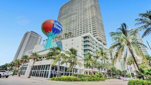 Un hotel moderno con una llamativa escultura esférica, varios pisos y palmeras.