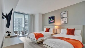 Una habitación de hotel con dos camas, un escritorio y un ventanal con vistas a la ciudad.