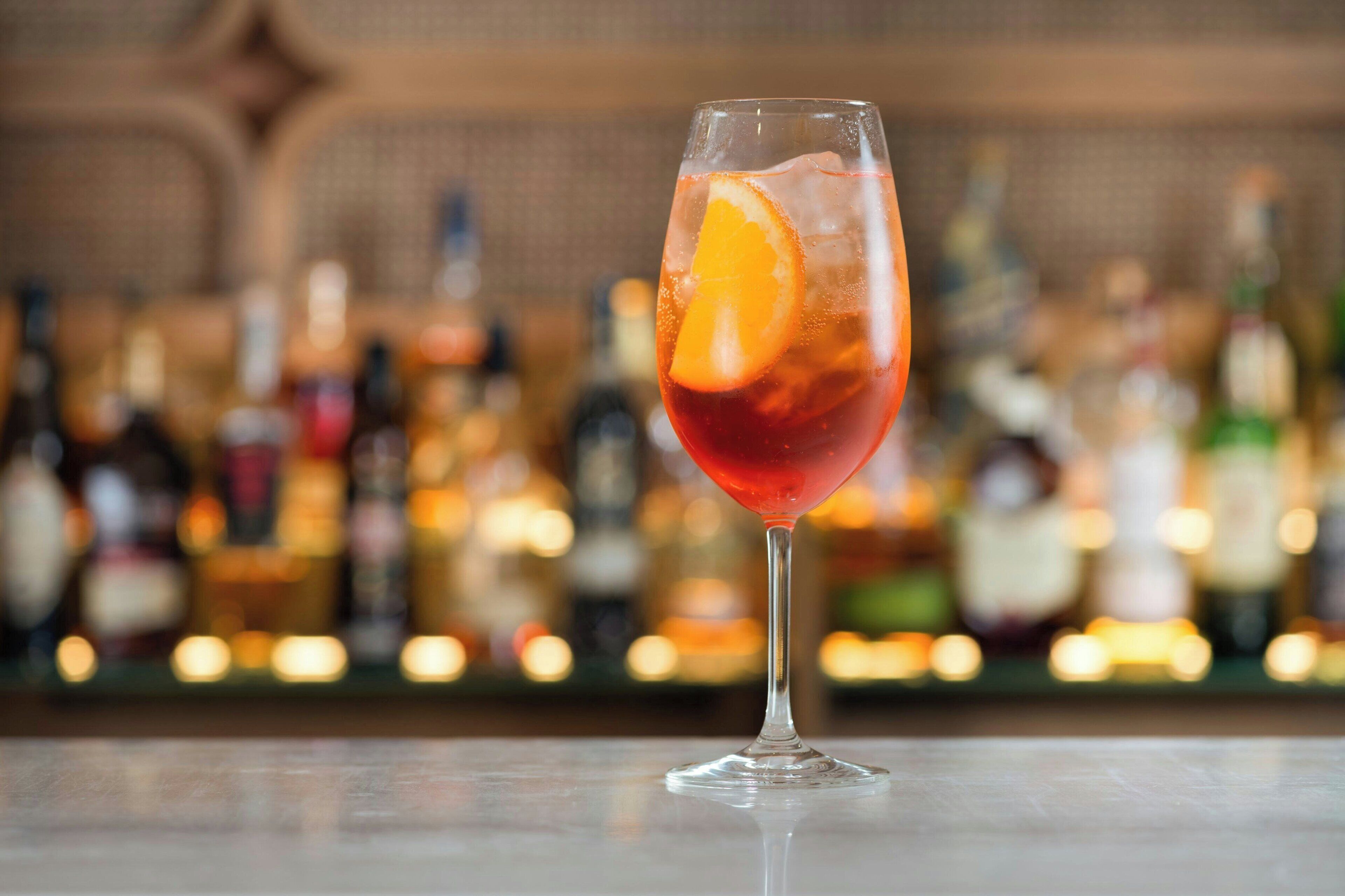 A cocktail glass with an orange slice on a bar counter.