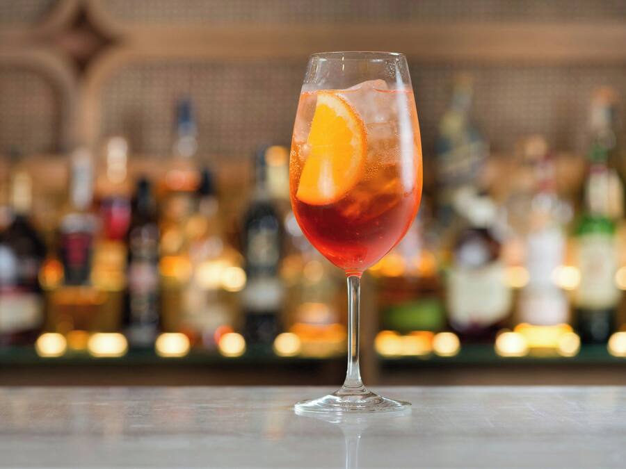 A cocktail glass with an orange slice on a bar counter.