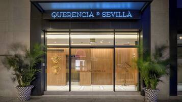 Entrada moderna de hotel con un letrero llamativo que dice "QUERENCIA P SEVILLA".