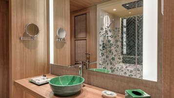 A modern bathroom with a wooden vanity, a green ceramic sink, and a large mirror.