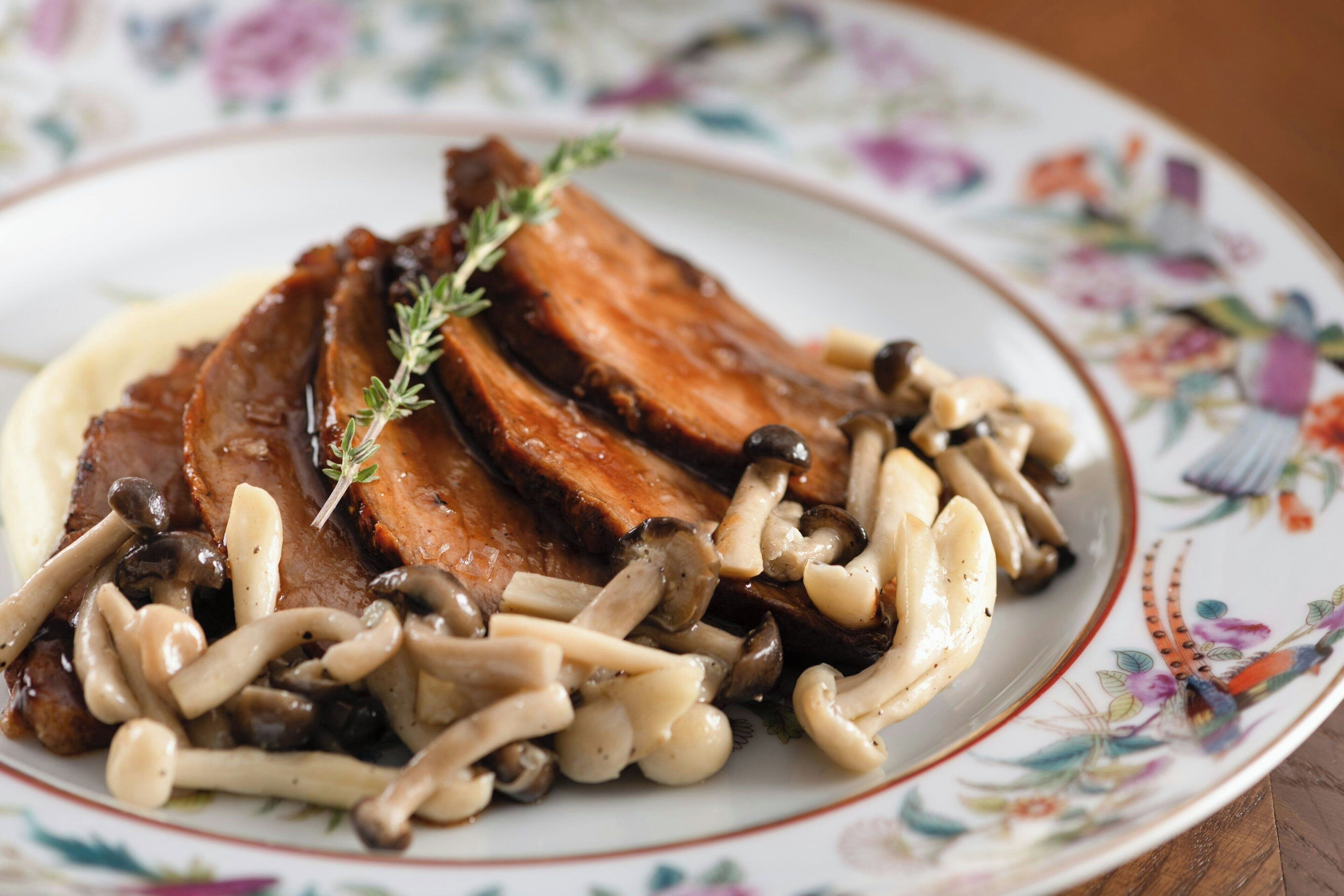 Un plato de comida con carne y champiñones.