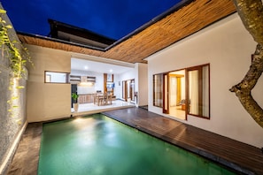 A modern house with a swimming pool, wooden deck, and a dining area. - The Dewi Villa Canggu (Tumbak Bayuh)