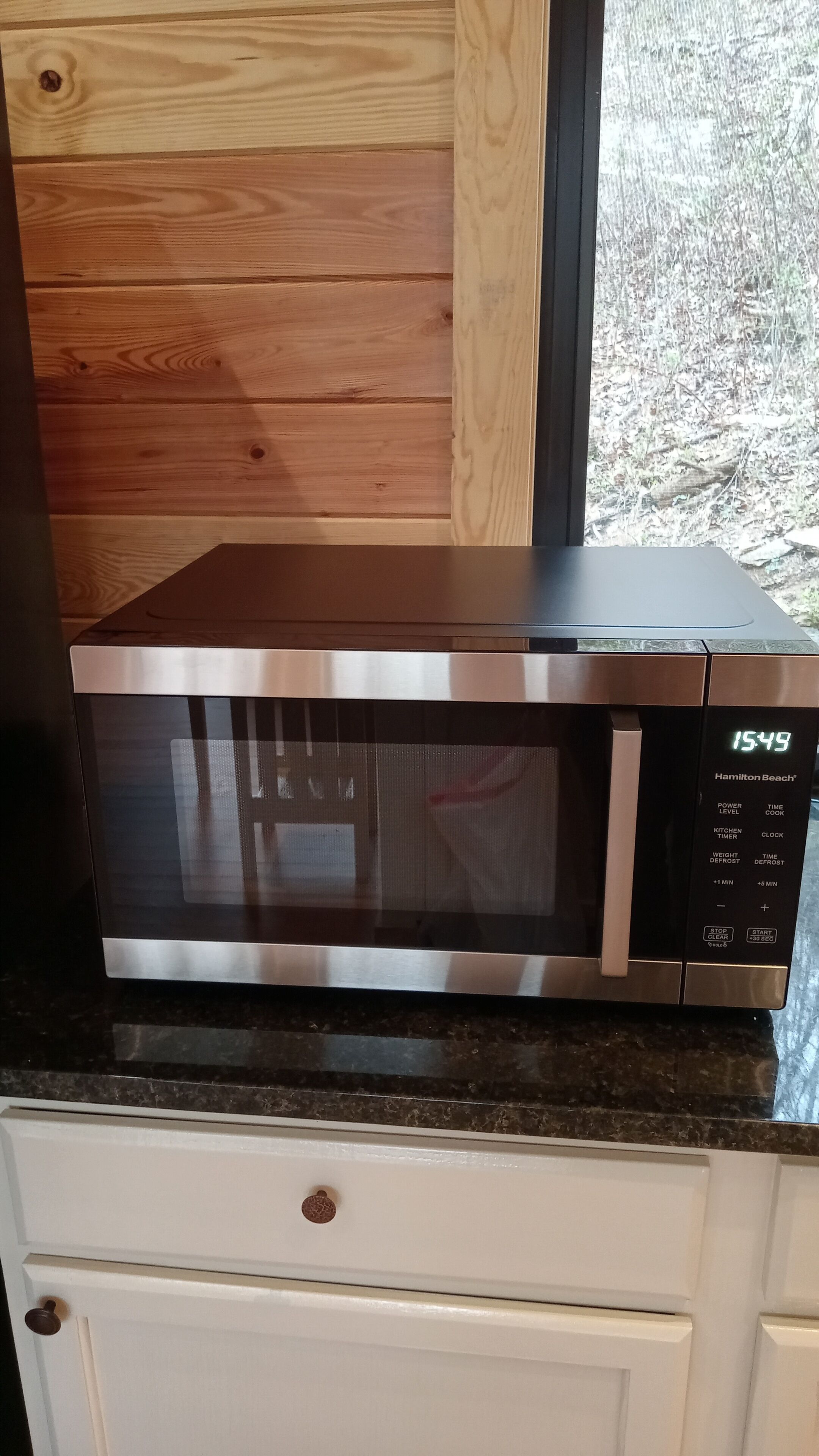 A stainless steel microwave oven with a digital display on a kitchen counter.