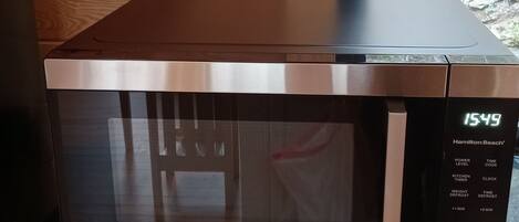 A stainless steel microwave oven with a digital display on a kitchen counter.