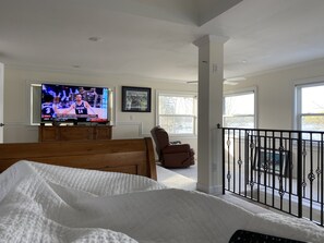 Relax in this serene bedroom with a large bed, TV, and balcony offering a view.