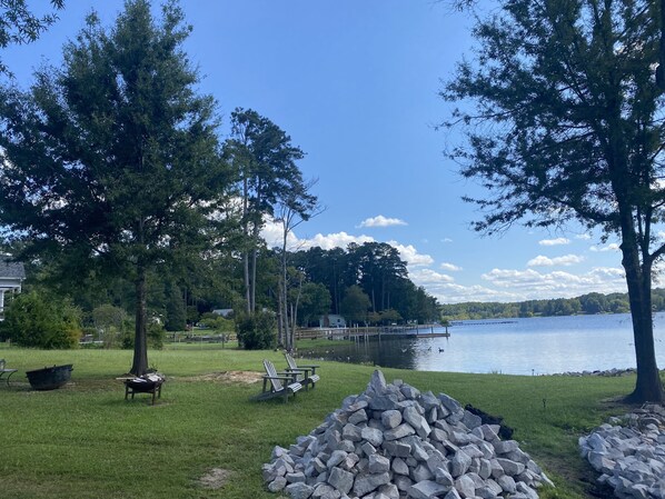 Relax by the serene lake with Adirondack chairs and a dock extending into the water.