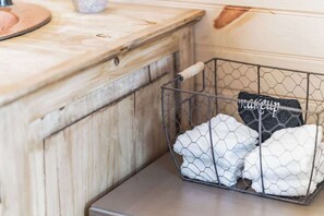 A kitchen with a wooden countertop, a wire basket containing folded towels, and a small metal container on the counter. - Romantic Stay Right On Main St! (Fredericksburg)