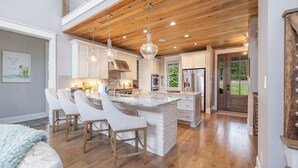 A spacious kitchen with a central island, wooden ceiling, and pendant lighting. - The Oasis at Lake Gaston - Heated Pool, Hot Tub, Pontoon Boat Rental Included! (Littleton)