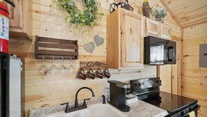 Una cocina tipo cabaña de madera con pileta, cafetera, microondas y cocina.