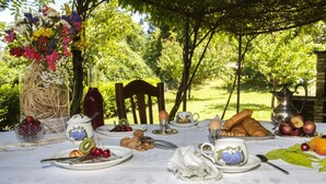 Une table de jardin dressée pour un repas en plein air, avec différents plats et un vase rempli de fleurs.