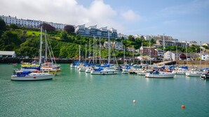 A marina with multiple boats docked, a waterfront view, and buildings in the background. - 5 Bed in Ilfracombe (oc-stagn) (Ilfracombe)