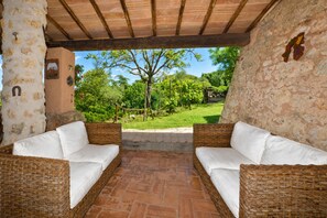 A covered patio with wicker furniture and a view of a garden. - Il Fortino (Monteriggioni)