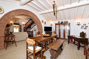 A spacious living area with a wooden dining table, comfortable seating, a fireplace, and a television.