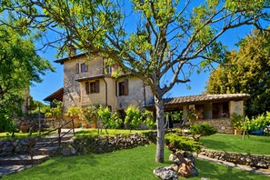 A stone building with a garden, a pergola, and a stone wall.