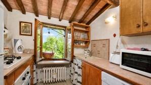 A compact kitchen with a window, wooden cabinets, a built-in oven, and a dishwasher.