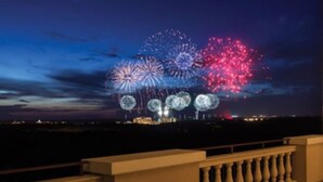 Ein Balkon mit Brüstung, der auf einen Nachthimmel mit Feuerwerk blickt.